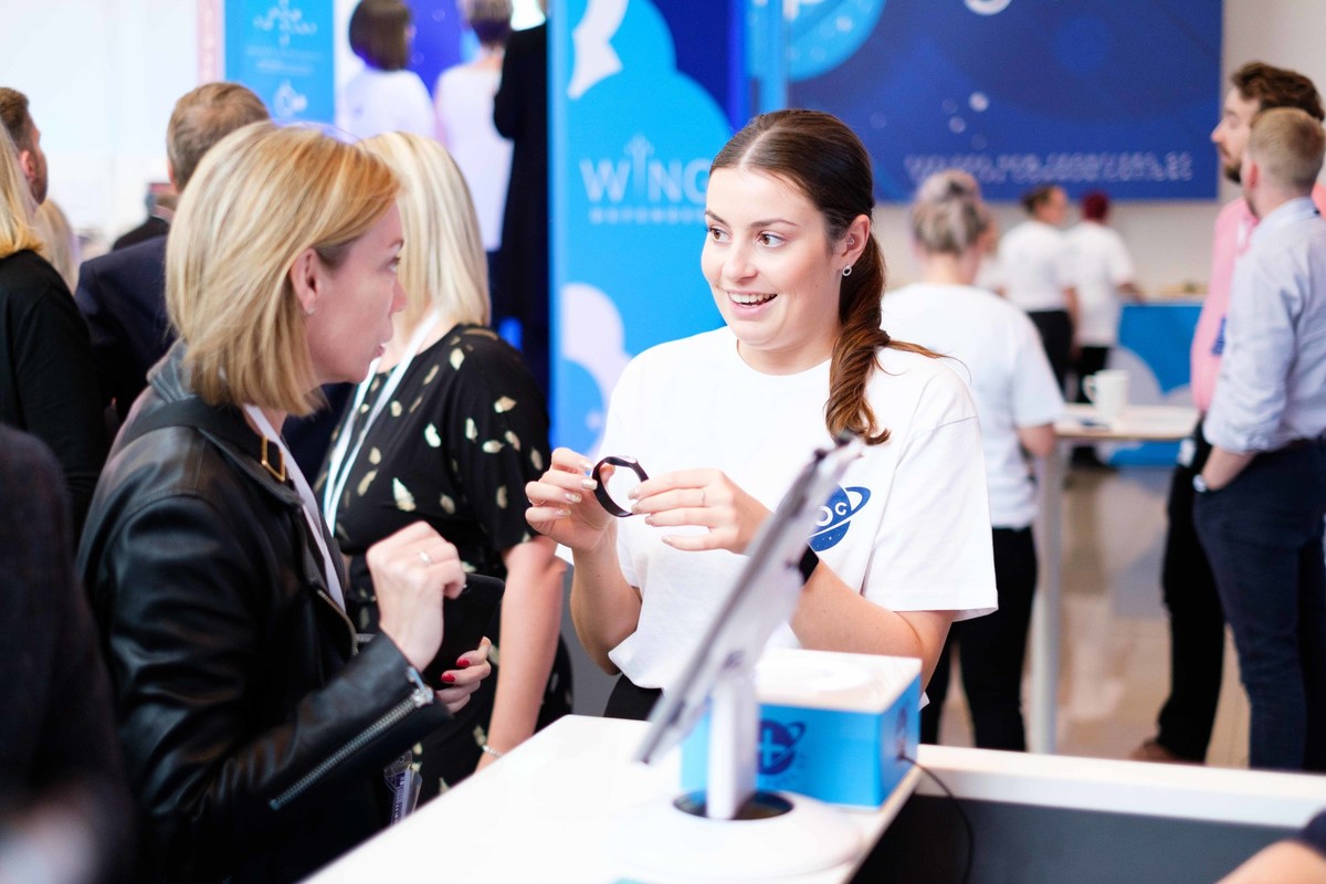 A woman giving an RFID wristband to a delegate.