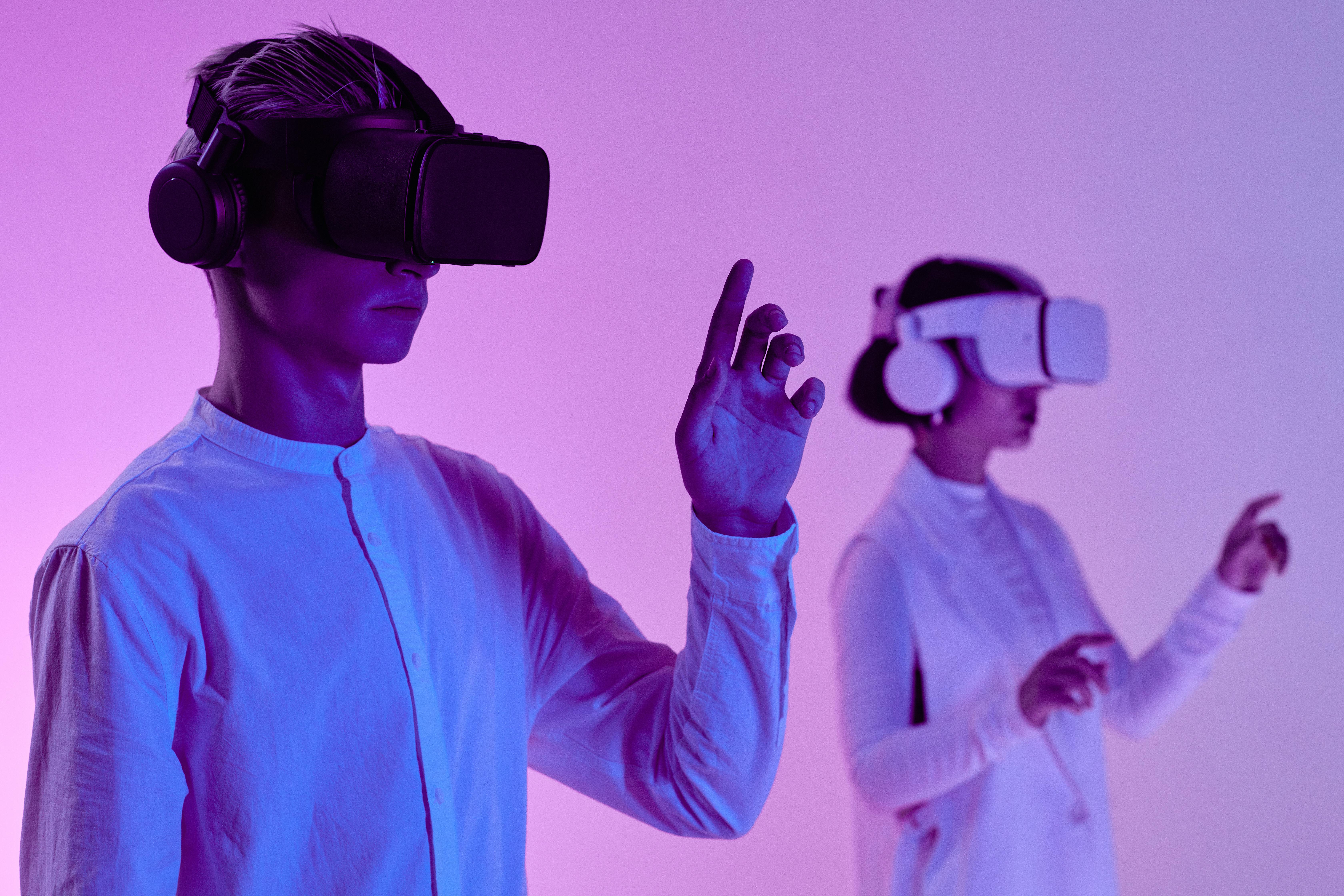 Two people in a white, purple-lit room, using vr headsets.